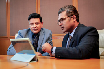 Two indian businessman discussing and using digital tablet