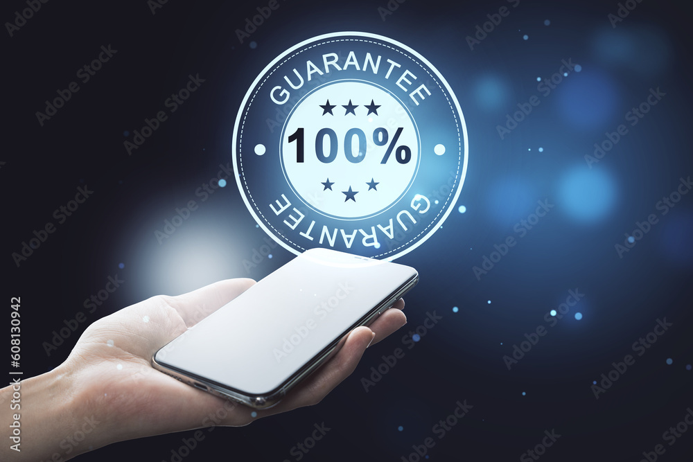 Poster close up of female hand holding smartphone with glowing 100% guarantee stamp hologram on dark backgr