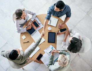 Meeting, handshake and overhead with a business team sitting around a table in the office at work....