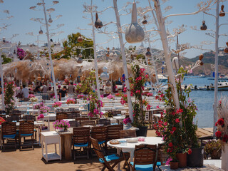 Bodrum summer travel to Turkey. Aegean fish restaurant table in Gumusluk Town, Bodrum, Turkey. Restaurant tables and chairs are in the sea