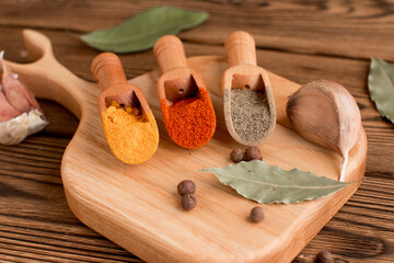 Fototapeta na wymiar spices for cooking. Black pepper, turmeric and red pepper with bay leaf and garlic on a wooden background