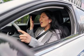 Frustrated Chinese woman screaming while driving a car