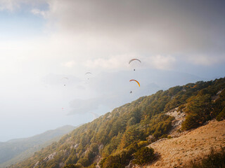 Paragliding in sky. Paraglider tandem flying over sea and mountains in cloudy day. view of...