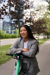 Portrait of Chinese woman riding on electric scooter in business outfit