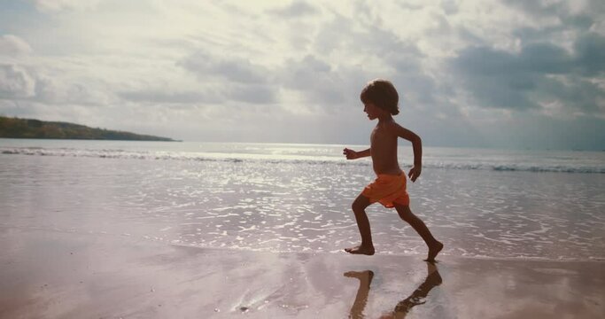 Boy little dreamer run barefoot on the beach. Concept of happy childhood