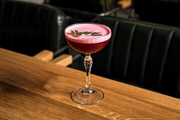 A pink sour alcoholic clover club raspberry cocktail with foam served in a coupe glass, garnished...