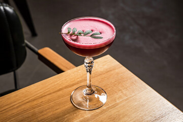 A pink sour alcoholic clover club raspberry cocktail with foam served in a coupe glass, garnished with a green sprig