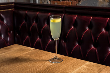 French 75 cocktail made of gin, lemon juice, sugar simple syrup, prosecco sparkling wine served in a flute glass garnished with lemon twist, on a wooden table in restaurant or bar, horizontal photo - 608136921