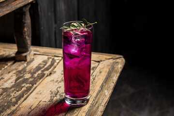 Gin and tonic cocktail made with purple gin served on ice in a highball cocktail glass garnished with green sprig - 608138166