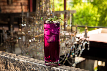Gin and tonic cocktail made with purple gin served on ice in a highball cocktail glass garnished with green sprig