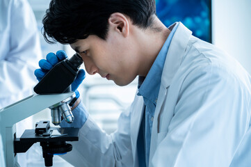 A male scientist conducting research under a microscope