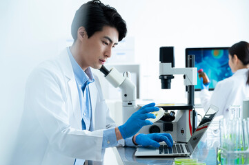 Young male Asian researchers work in a laboratory with digital gadgets.