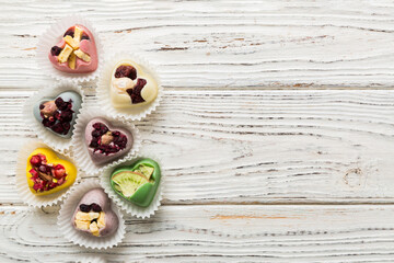 chocolate sweets in the form of a heart with fruits and nuts on a colored background. top view with space for text, holiday concept