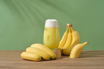 A glass of banana juice placed on a wooden podium, decorated with bunches of banana. Bananas...