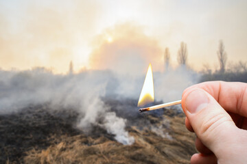Burnt field in countryside with burning match on the foreground. Concept of big wildfire caused by a match