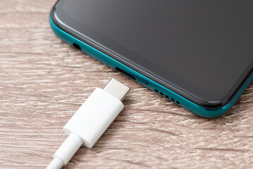 Close up of usb type-c cable near mobile phone. Connecting usb c cable to the phone for charging - obrazy, fototapety, plakaty