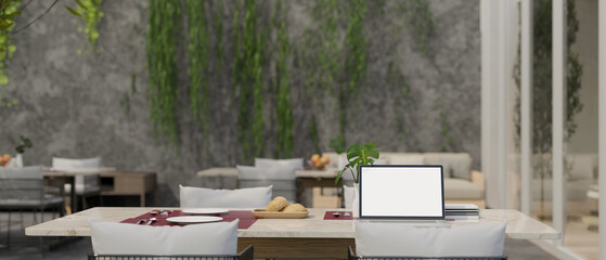 A laptop mockup is on a dining table in a beautiful modern loft restaurant.