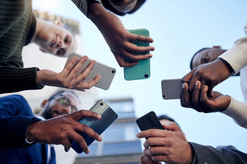 Phone, low angle and group of business people networking in city outdoor. Smartphone, circle and team network together on social media, web email or online scroll on mobile app, tech or communication