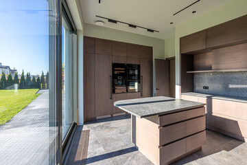 Plakat Empty kitchen with a marble table in the center, wooden cabinets in a modern minimalist style and a large panoramic window