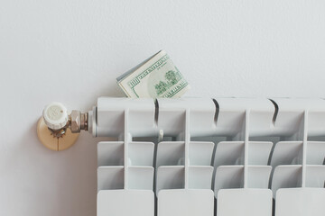 a stack of money dollars on a white battery heating radiator on a white wall, the concept of saving utility bills, Energy crisis