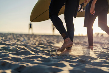 Surfers' feet walking on the sand beach.