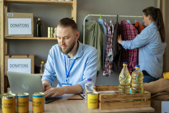Young volunteers using laptop working at charity center. Charity, donation and volunteering - Powered by Adobe