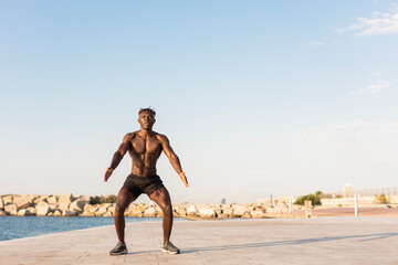Fitness training outdoors. Handsome African man doing exercises outside. Muscular man training.