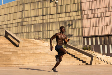 Fitness training outdoors. Handsome African man running. Muscular man training.