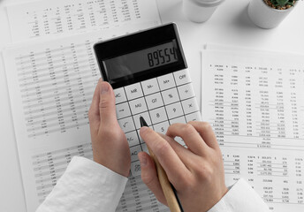 Accountant using calculator on desk office on white background with financial statement. Top view
