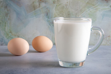 Glass of milk and two eggs on blue table