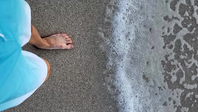 Top view barefoot guy walks along the sandy shore to the sea. Summer vacation or holiday close up POV. Slow motion vertical video