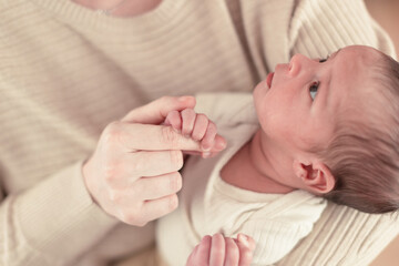 newborn child squeezes his mother's finger with his little hand