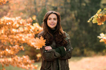 Autumn Fashion concept. Stylish girl in autumnal style posing on red maple leaf background outdoors. Autumn dream. Woman dreams in autumn fall. Beauty girl dream. Daydreamer woman.