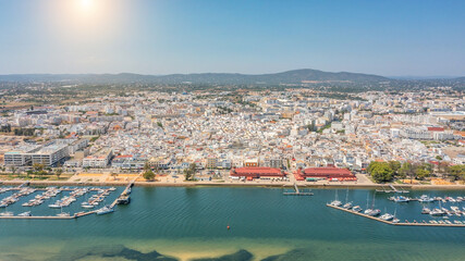 Aerial view of Portuguese fishing tourist town of Olhao with a view the Ria Formosa Marine Park. Sea port for yachts and Sun over the mountains