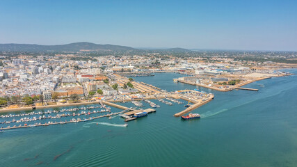 Fototapeta premium Aerial view of Portuguese fishing tourist town of Olhao with a view the Ria Formosa Marine Park. Sea port for yachts moored at the berths
