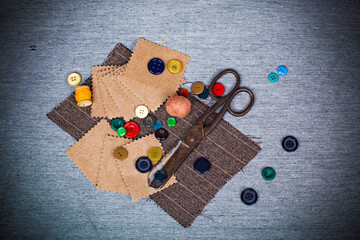 Scissors, threads, buttons, pieces of felt and fabric on a gray background. Needlework abstract background in retro style.