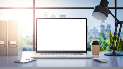 A laptop with a blank frameless screen mockup template is positioned on a table in an office interior, offering a front view, with office buildings in the background. 3d render