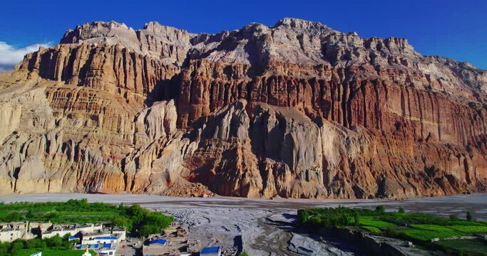Drone glides over unique dry mountains of Chuksang in Upper Mustang, Nepal. Alluring video with a backdrop of blue sky and river. Explore the captivating beauty of Annapurna Area.