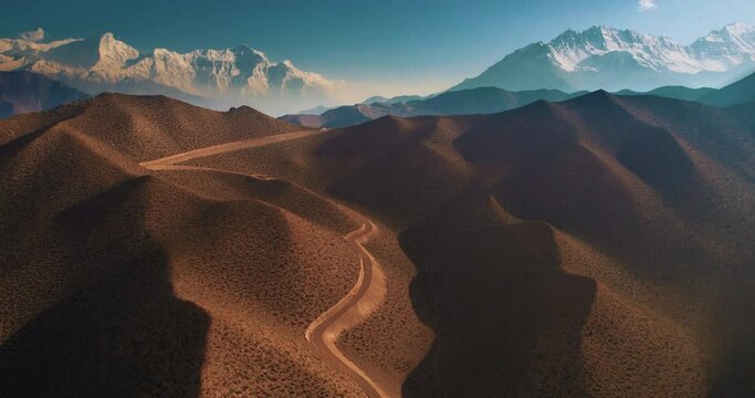 Captivating drone footage of road at deserted hills and mountain ranges in Ghyakar Village, Upper Mustang, Nepal. Stunning landscape with artistic structures. Discover the beauty of Annapurna Area.