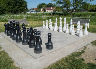 Szachownica z szachami w parku pośród zieleni. Duże szachy.
