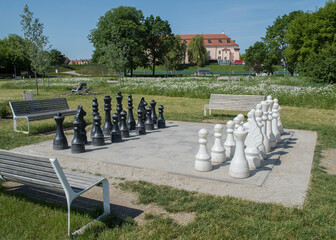 Szachownica z szachami w parku pośród zieleni. Duże szachy.