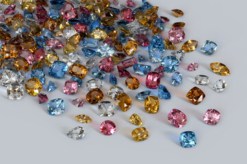 Variously cut, colored topaz stones scattered on white background.