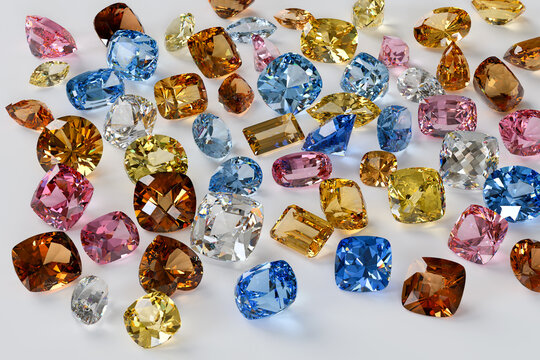 Variously cut, colored topaz stones scattered on white background.