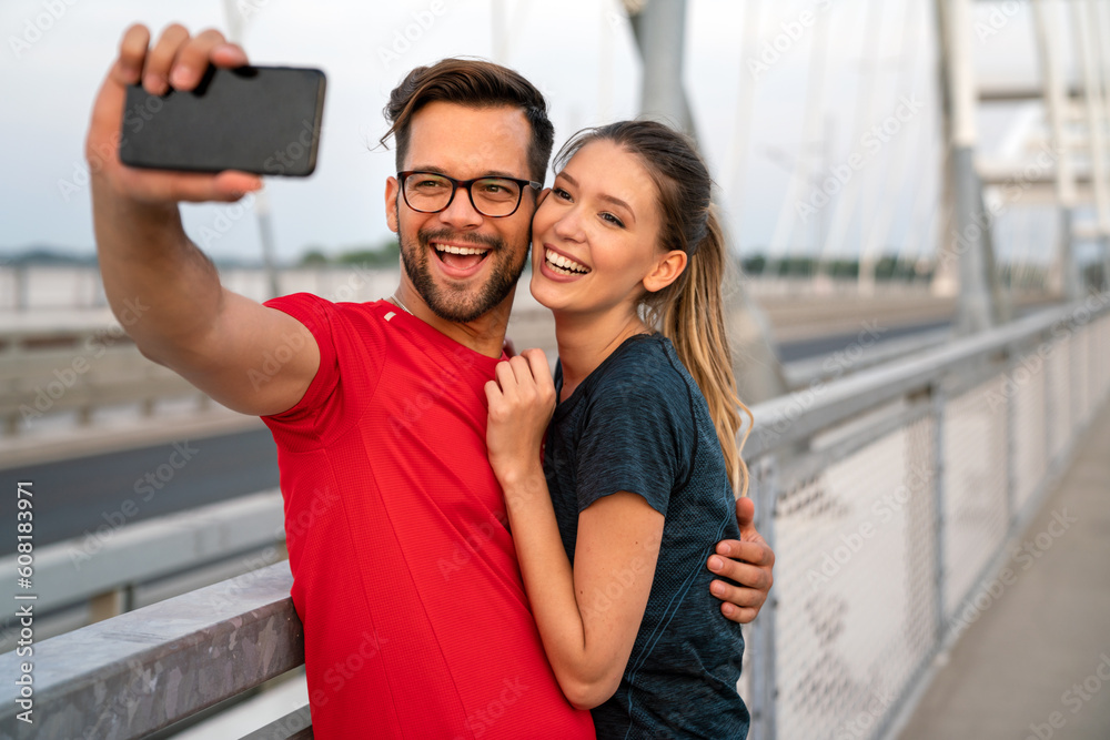 Wall mural fitness, sport, technology and lifestyle concept. two smiling people with smartphones outdoors