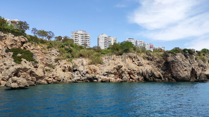 Blue Mediterranean sea, blue sky with white clouds and a rocky shore with a cliff