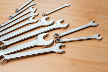 A set of working tools, different size wrenches on a brown wooden, bamboo background. Top view