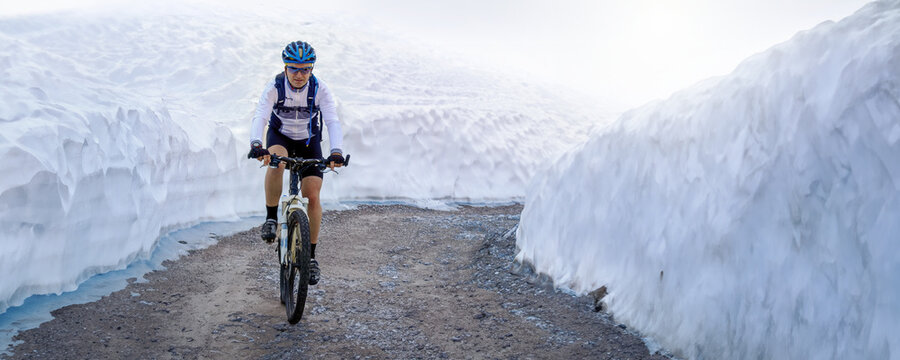 Mountainbiker kämfpt sich durch den Schnee einen Bergpfad hoch