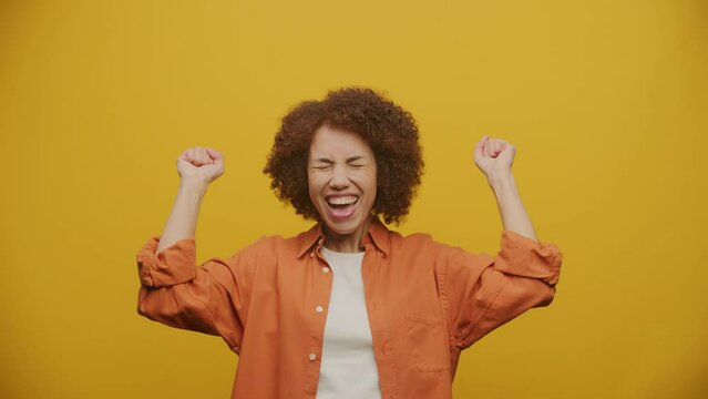 Woman Celebrating Success on Yellow Background