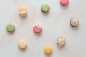 Flat lay of colorful macarons against a pink marble background
