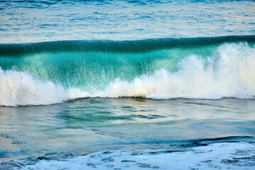 Smaragdfarbene Welle bricht am Strand 